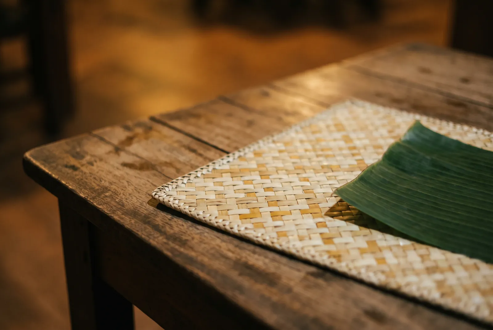 Woven banig placemat and banana leaf on a rustic wooden table