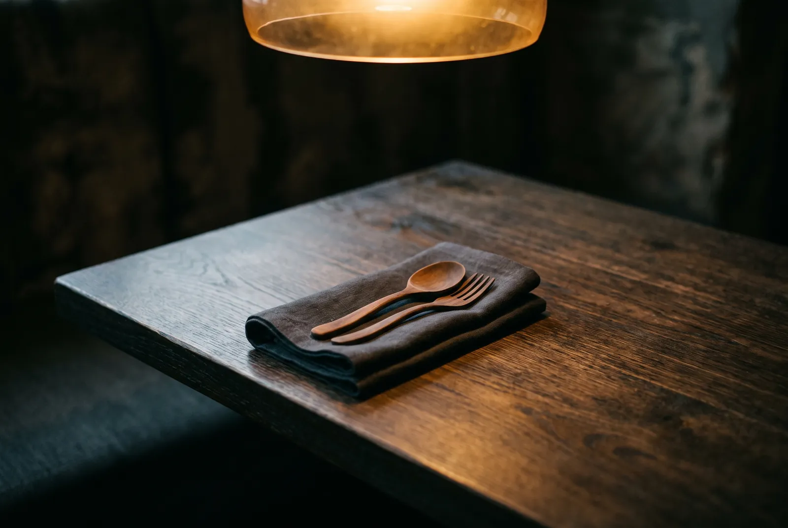 Dark wooden tabletop set with a linen napkin and wooden spoon and fork